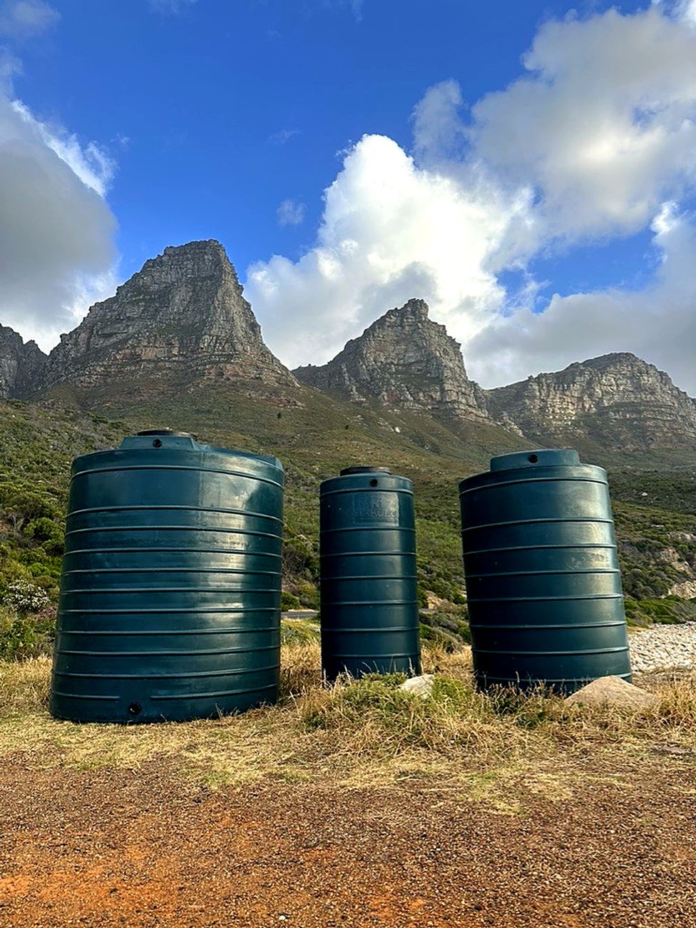 Three green water tanks below the mountains