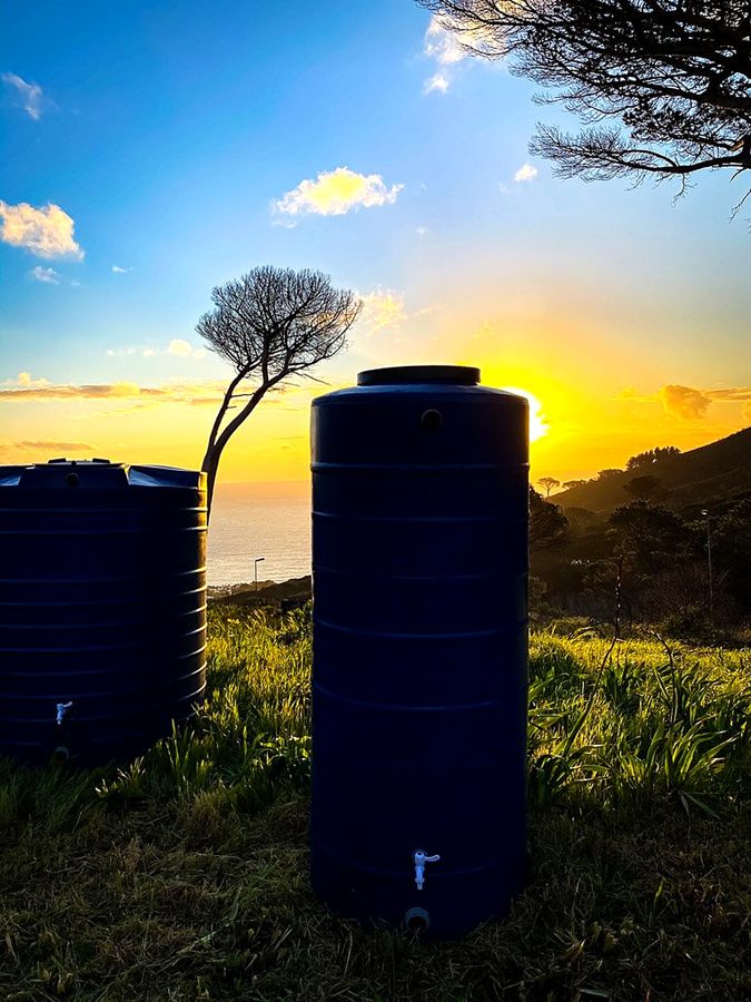 Blue water tanks on a hillside at sunset
