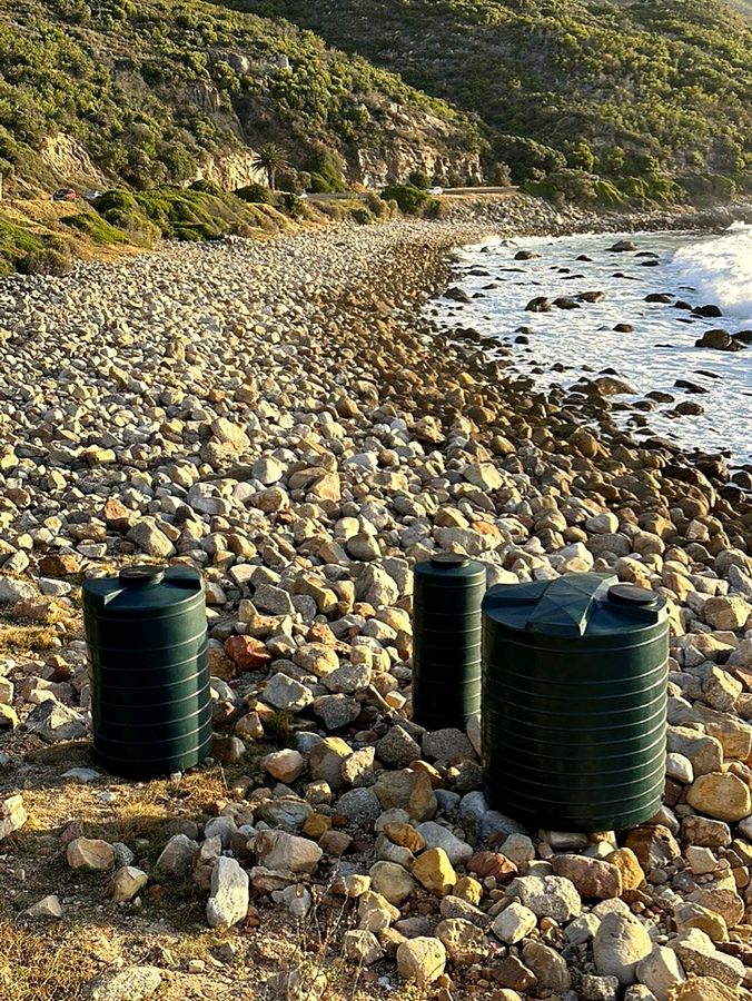 Green water tanks on a rocky shoreline